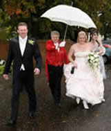 Toastmaster Richard Palmer assisting the bride into the wedding reception ensuring the wedding dress does not spoil in the rain!